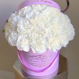 White carnation bouquet in a pink hatbox with ribbon handle