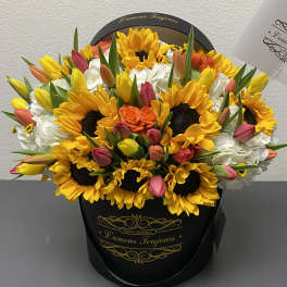 Bouquet of sunflowers, tulips, and white hydrangeas in a black hat box