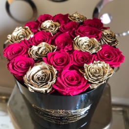 Pink and gold roses arranged in a black hat box