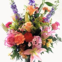 Mixed bouquet of pink, orange, and purple flowers in a glass vase