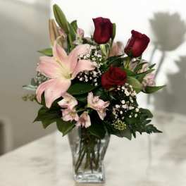 Bouquet of red roses and pink lilies in a clear glass vase