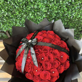 Large bouquet of red roses wrapped in black paper with a black ribbon
