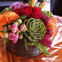 Colorful mixed flower arrangement in a round dark vase with succulents