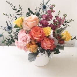 Mixed roses and thistle in a white vase