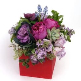 Purple and pink floral arrangement in a red box