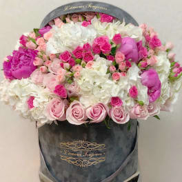 Large bouquet of pink and white roses in a gray hatbox