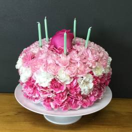 Pink and white floral cake with mint green candles on a pedestal stand