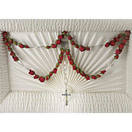 White funeral casket with red rose garlands and a small cross