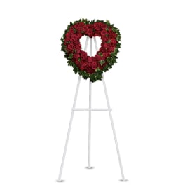Heart-shaped red rose wreath on a white easel stand