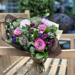 Bouquet of pink roses and purple flowers wrapped in brown paper