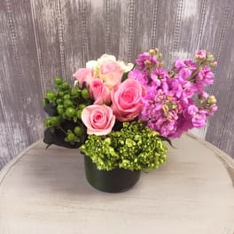 Pink roses and purple flowers arranged in a black container