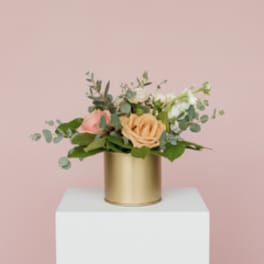 Peach and pink rose arrangement in a gold cylinder vase