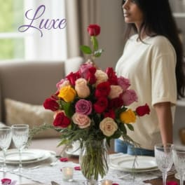 Mixed rose bouquet in a clear glass vase on a set dining table