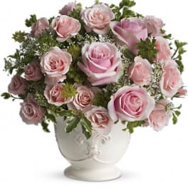 Pink roses arranged in a white urn vase