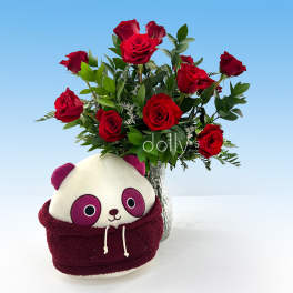 Red roses in a glass vase with a panda plush in front