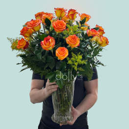 Bouquet of orange and yellow roses in a clear glass vase