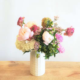 Pastel floral arrangement in a white vase with pink and cream blooms