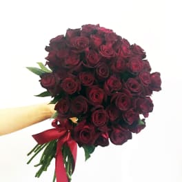 Handheld bouquet of deep red roses tied with a red ribbon