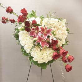 Heart-shaped rose arrangement with pink lilies on a stand