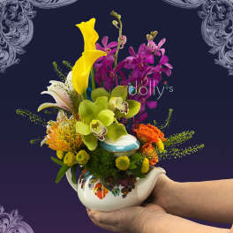 Colorful bouquet in a floral teapot with orchids, calla lilies, and roses