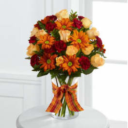 Bouquet of orange daisies and red roses in a clear glass vase