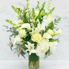 White and pale yellow flowers arranged in a clear glass vase