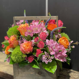 Bright pink and orange roses with green blooms in a rustic wooden box.