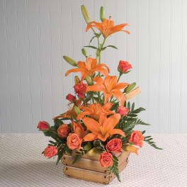 Orange lilies and coral roses in a wooden basket