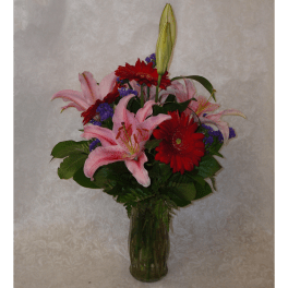 Bouquet of pink lilies and red gerbera daisies in a glass vase