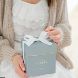 Person holding a blue gift box with a white ribbon
