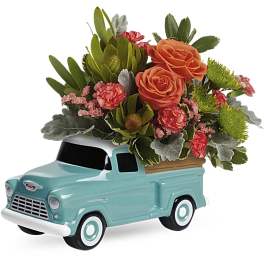 Flower arrangement in a turquoise ceramic truck planter