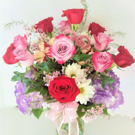 Bouquet of red and pink roses with purple flowers in a glass vase