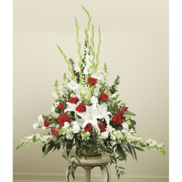 Tall red and white floral arrangement in a glass vase on a stand