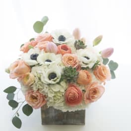 Peach and white floral arrangement in a square wooden container