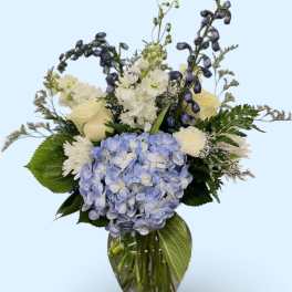 Blue hydrangea bouquet with white flowers in a clear glass vase
