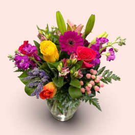 Mixed bouquet of bright flowers in a clear glass vase