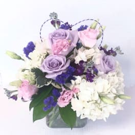 Lavender and pink roses with white hydrangeas in a glass vase