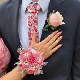 Pink rose corsage and boutonniere on a dark suit with a floral tie