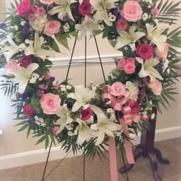 Large floral wreath with pink roses and white lilies on a stand