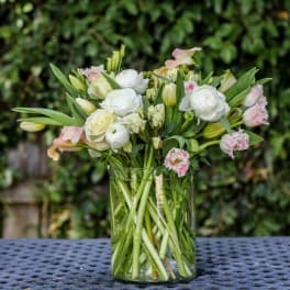 White and pale pink flowers arranged in a clear glass vase