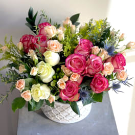 Pink and cream roses arranged in a white patterned bowl