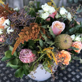Mixed bouquet of peach and white roses in a white vase