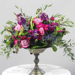 Pink and purple rose arrangement in a silver pedestal vase