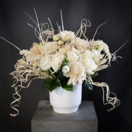 Cream floral arrangement in a white vase with curly decorative accents