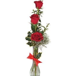 Three red roses in a clear glass vase with a red ribbon