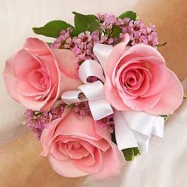 Pink rose wrist corsage with white ribbon and small purple flowers