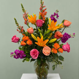 Colorful mixed bouquet in a clear glass vase with roses and lilies