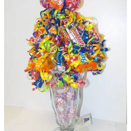 Candy bouquet in a clear glass vase with colorful curled ribbons