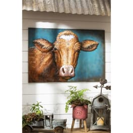 Cow painting above rustic potted plants and metal decor.