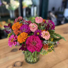Bright mixed bouquet of pink, orange, and purple flowers in a glass vase